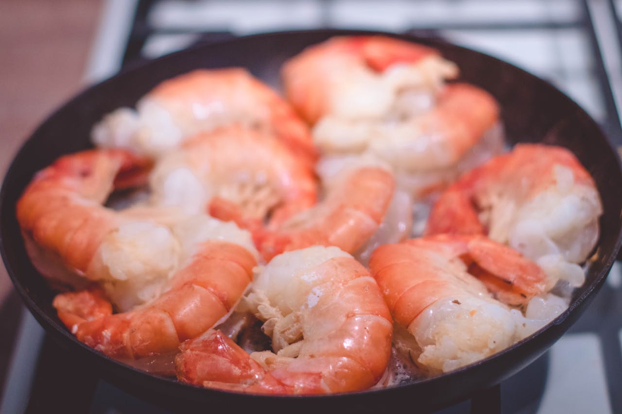 about-us-02 Delicious close-up of prawns sizzling in a frying pan, perfect for seafood lovers.